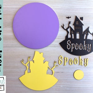 May include: A laser cut file for a spooky Halloween themed craft project. The file includes a purple circle, a black silhouette of a haunted house with the word "Spooky" underneath, a yellow silhouette of a haunted house, and the word "Spooky" in a decorative font.