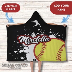 May include: Black hooded blanket featuring a yellow softball graphic and the name "Maddie" in red and white. The blanket also has a white silhouette of a softball player and the text "Squad Goals Custom Wear".