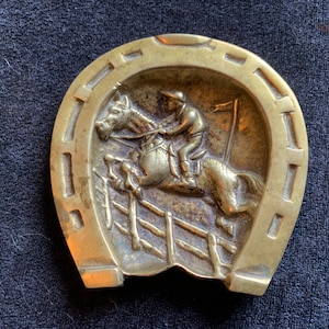 Cavallo da corsa d&#39;ottone d&#39;annata e cavaliere su un ferro di cavallo fortunato