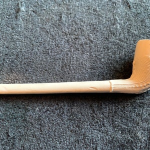 Puede incluir: Una pipa de cerámica blanca con una boquilla curva y un diseño decorativo en la cazoleta.