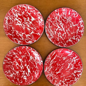 May include: Four round plates featuring a vibrant red base color with a white marbled or swirled pattern throughout the surface. Each plate has a thin, dark rim around the circular edge, creating a consistent look across the set of four items.