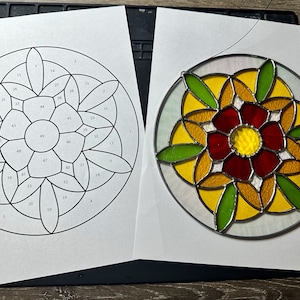 May include: A stained glass pattern with numbered sections, and a completed stained glass piece depicting a flower with red, yellow, and green glass.