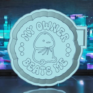 以下が含まれることがあります： 「My Owner Beats Me」という文字が円形に書かれた、薄い青色の丸いバッジ。バッジの中央には、丸い頭、2つの目、口を持つ薄い青色の生き物のキャラクターが描かれている。キャラクターは、細長い体と2本の腕と2本の脚を持っている。
