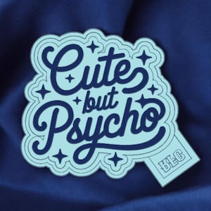 May include: A light blue sticker with the words "Cute but Psycho" in a dark blue, stylized font. The sticker has a light blue border with star accents and a small rectangle with the initials "BLG".