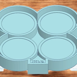 May include: A light blue plastic mold with four circular compartments connected in a figure-eight shape. The mold has a rectangular base with the letters "RLG" and a measurement label in inches.