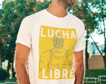May include: White t-shirt featuring a yellow graphic of a masked wrestler. The graphic reads "LUCHA LIBRE" in blue and white text.