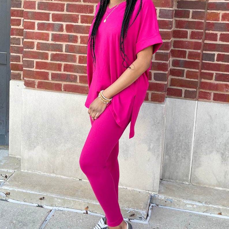 Op de afbeelding: Een roze twee-delige outfit met een loszittende, korte mouwen top en leggings.