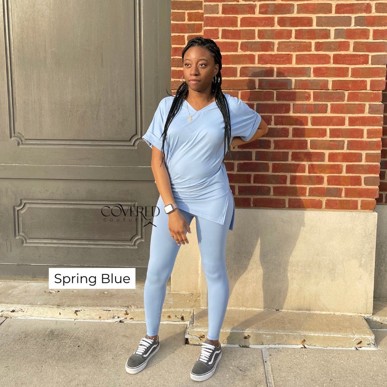 Op de afbeelding: Een lichtblauwe twee-delige outfit met een lang mouwloos top en leggings. De top heeft een V-hals en een zijsplit. De outfit heet "Spring Blue" en is van het merk "Covered Couture".