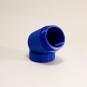 May include: A bright blue, cylindrical container with a ridged exterior. The container is open, revealing a hollow interior. The lid is also blue and ridged. The container is resting on its side, with the lid beside it.