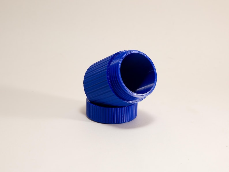 May include: A bright blue, cylindrical container with a ridged exterior. The container is open, revealing a hollow interior. The lid is also blue and ridged. The container is resting on its side, with the lid beside it.