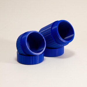 May include: Two small, cylindrical, royal blue containers with ribbed exterior textures. Each container consists of a circular base and a matching open-topped vessel, featuring visible screw threads along the upper rims for secure closure.