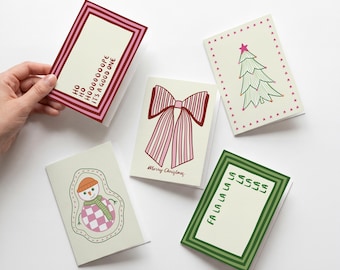 May include: Four rectangular greeting cards with festive designs. One features a red striped border and text reading HO HO HOOOOOPE IT'S A GOOD ONE. Another shows a pink bow with Merry Christmas text. A third displays a green tree with stars. The last has a snowman and a green striped border with text reading FA LA LA LA LA LA LA LA.