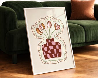 Puede incluir: Una lámina enmarcada con una ilustración de líneas de un jarrón a cuadros en tonos marrón y rosa. El jarrón contiene cuatro tulipanes con pétalos rosas y naranjas. Todo el arreglo floral está delineado por un borde decorativo ondulado.