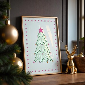 Puede incluir: Una l&aacute;mina enmarcada que muestra un &aacute;rbol de Navidad estilizado con l&iacute;neas verdes, una estrella rosa en la punta y peque&ntilde;os adornos coloridos, rodeado por un borde de estrellas rosas sobre un fondo claro, en un marco dorado fino.