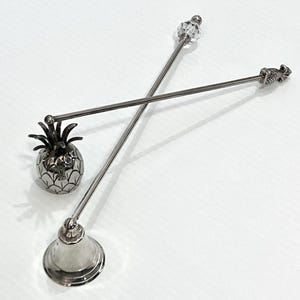 Puede incluir: Removedores de cóctel plateados con extremos decorativos, incluyendo una piña y una cuenta de cristal. También hay un palillo de cóctel plateado en forma de piña. Estas herramientas de bar están diseñadas para mezclar bebidas.