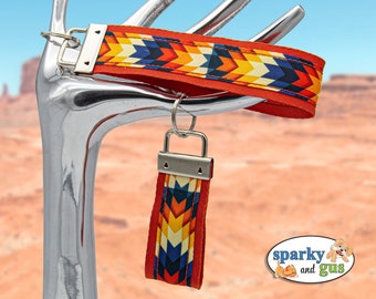 May include: A red, white, blue, and orange patterned key chain with a silver key ring. The key chain has a geometric pattern and is attached to a silver key ring.