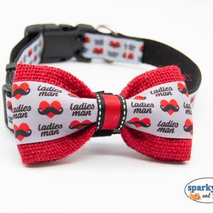 May include: Red burlap bow tie with a white ribbon featuring a repeating pattern of red hearts and black mustaches with the text "Ladies Man".