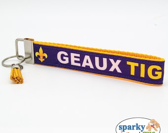 May include: Purple and gold key chain with a fleur-de-lis and the text "GEAUX TIG"
