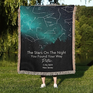 May include: A woven blanket featuring a night sky design with constellations and a teal and black color scheme. The blanket has a fringed edge and includes the text "The Stars On The Night You Found Your Way", the name "Peter", the date 7/10/2019, and "New Jersey".
