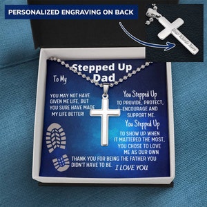 May include: A silver necklace with a cross pendant comes in a blue box with a heartfelt message for a father. The message reads "You may not have given me life, but you sure have made my life better! You stepped up to provide, protect, encourage and support me. You stepped up to show up when it mattered the most, you chose to love me as our own. Thank you for being the father you didn't have to be. I love you."