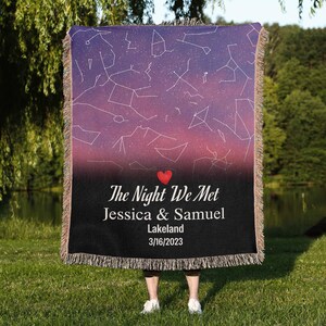 May include: A personalized throw blanket featuring a celestial design with constellations on a purple and pink gradient background. The blanket has a black border with the text "The Night We Met", names, and a date.