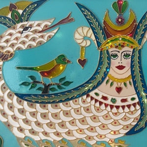 May include: A framed, colorful artwork featuring a mythical creature with a woman's face, a serpent's body, and a bird. The artwork is set against a turquoise background and includes floral and decorative elements in gold, red, and white.