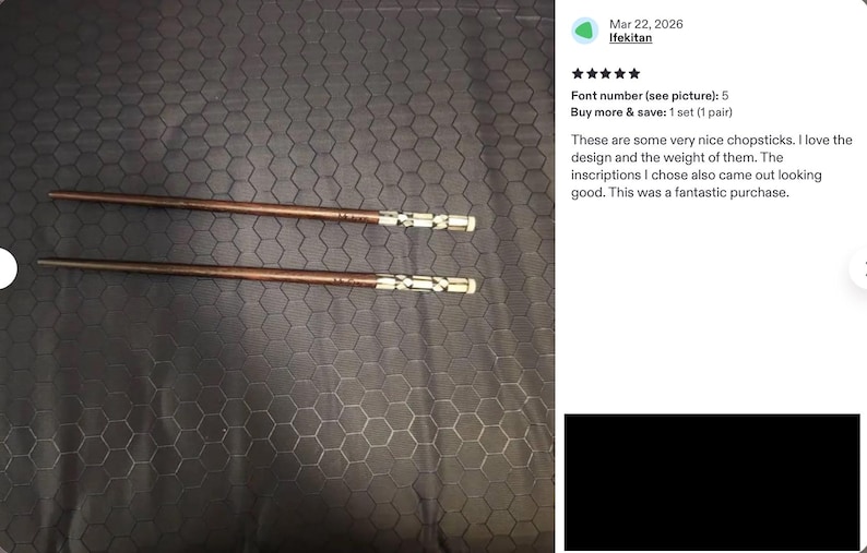 K&ouml;nnte beinhalten: Ein Paar braune Essst&auml;bchen aus Holz mit einem dekorativen silberfarbenen Metallband am Griffende, das ein geometrisches Ausschnittmuster aufweist. Die St&auml;bchen haben ein glattes, konisches Design und liegen horizontal vor einem dunklen Hintergrund.