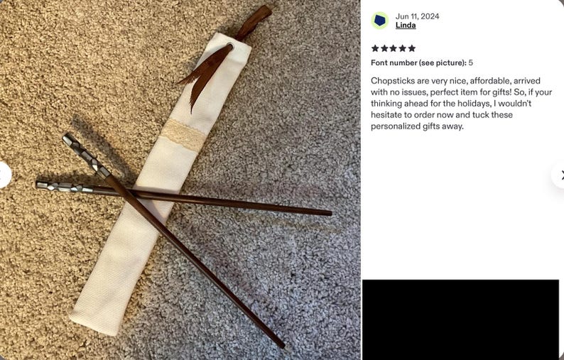 K&ouml;nnte beinhalten: Ein Paar dunkelbraune Essst&auml;bchen aus Holz mit metallisch silberfarbenen, sechseckigen Endst&uuml;cken, begleitet von einer langen, schmalen Aufbewahrungstasche aus cremefarbenem Stoff mit einem braunen Lederband als Verschluss.