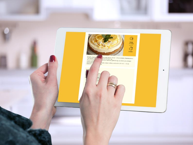 Hands viewing the Lemon Cheesecake recipe page on a tablet in a kitchen setting.