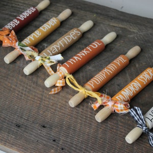 May include: Seven miniature rolling pins with fall-themed sayings, including "Apple Cider", "Hayrides", "Pumpkin Pie", and "Hello Fall". Each pin is decorated with a different colored ribbon.
