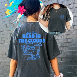May include: A black oversized t-shirt with a blue graphic of a cartoon cloud with a face and the text "Keep Your Head In The Clouds".