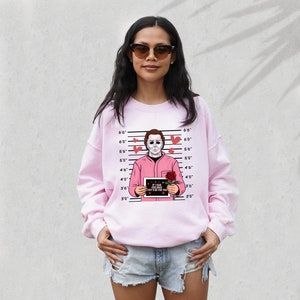May include: Pink sweatshirt with a graphic of a man in a pink shirt holding a sign that says "If I had feelings, they'd be for you." The man is surrounded by hearts and a red rose. The graphic is set against a white background with a height chart.