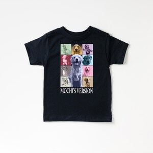 K&ouml;nnte beinhalten: Schwarzes T-Shirt mit einem Raster aus farbenfrohen Hundeportr&auml;ts. Das zentrale Bild ist ein hellfarbiger Hund. Der Text "MOCHI'S VERSION" ist darunter in Wei&szlig; gedruckt. Das Shirt besteht aus einem weichen Material.