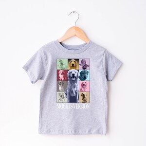 K&ouml;nnte beinhalten: Hellgraues Kinder-T-Shirt mit einer farbenfrohen Grafik eines Golden Retrievers. Die Grafik ist ein Raster aus neun Quadraten, jedes mit einem unterschiedlich farbigen Hintergrund und einem Portr&auml;t eines Golden Retrievers. Der Text "Mochi's Version" steht darunter.