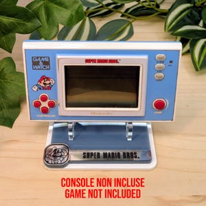 Può includere: Un supporto per console Game & Watch blu chiaro con il logo Super Mario Bros. Il supporto presenta una grafica di Mario e il testo "Super Mario Bros.". La console non è inclusa. Il supporto è progettato per una console Nintendo Game & Watch.