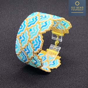 Puede incluir: Un brazalete de cuentas azules y doradas con un patrón geométrico. El brazalete tiene un cierre de broche.