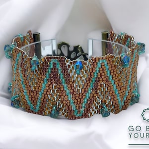 May include: A wide beaded bracelet featuring a brown and turquoise chevron design. The bracelet is embellished with turquoise crystal beads and has a clear clasp. The words "GO BEAD YOURSELF" are visible in the image.