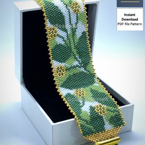 May include: A green, white and gold beaded bracelet with a floral pattern. The bracelet is in a white box with a black interior. The text "Go Bead Yourself" is on the top right corner of the image.