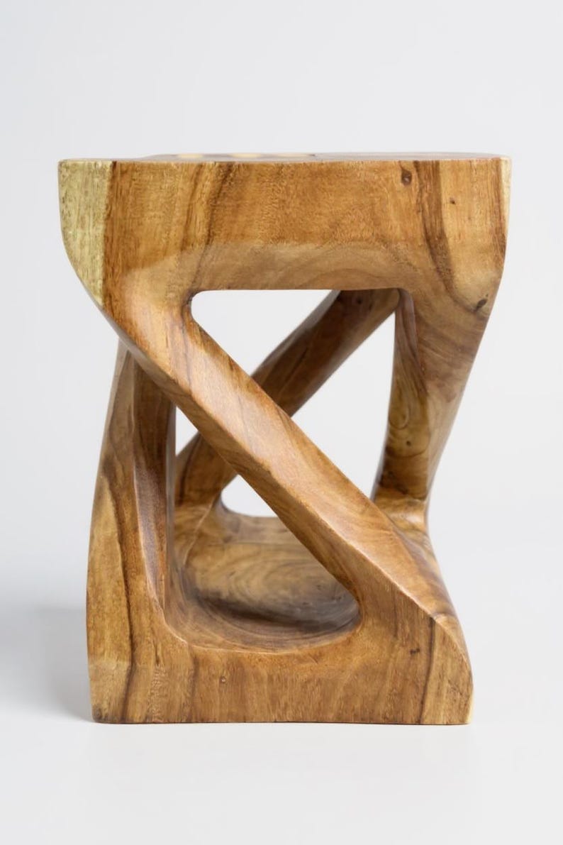 May include: A wooden stool with a unique, sculptural design. The stool is made of light brown wood and features an open, interwoven structure. The top and base are rectangular, and the sides have a twisted, geometric shape. The wood grain is visible.