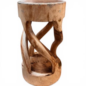 Può includere: Uno sgabello in legno naturale dal design unico. Lo sgabello presenta un piano e una base rotondi collegati da supporti curvi e intagliati in modo intricato. La venatura del legno è visibile, mostrando le variazioni naturali di colore. Per uso interno.
