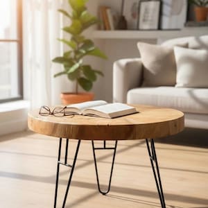 Könnte beinhalten: Ein runder Couchtisch aus Holz mit schwarzen Haarnadelbeinen aus Metall. Ein offenes Buch und eine Brille liegen auf der Tischoberfläche. Der Tisch befindet sich in einem Wohnzimmer mit Sofa und Topfpflanze.
