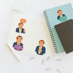 May include: A collection of stickers featuring a cartoon man in a blue blazer. The stickers have text bubbles with phrases like "It's me, Stan!" and "I can't help it. I'm a passionate man." One sticker is on a light blue spiral notebook.