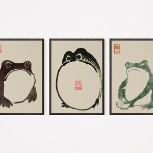 May include: Three framed black and white ink drawings of frogs. The first frog is sitting with its mouth open. The second frog is curled in a circle. The third frog is sitting with a bowl in front of it.