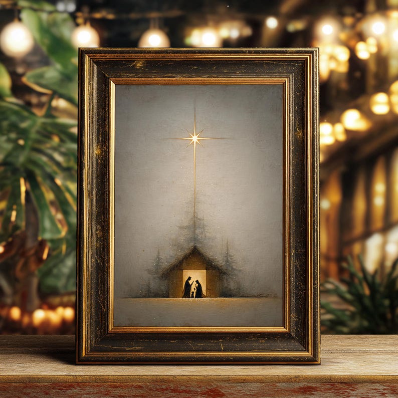May include: A framed artwork depicting a nativity scene. The image features a star shining above a small building with silhouettes of figures inside. The frame is dark with gold accents, set against a blurred background of lights and greenery.