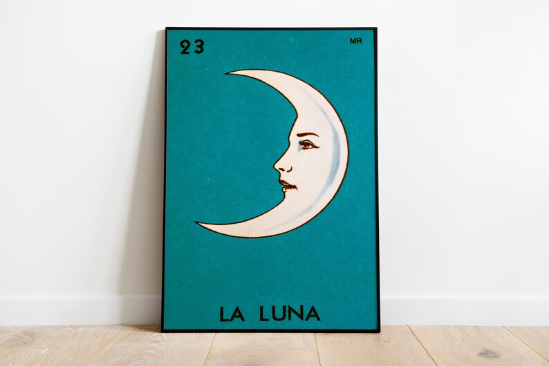 K&ouml;nnte beinhalten: Eine Loteria-Karte im Vintage-Stil mit einer Illustration eines zunehmenden Mondes. Die Karte ist blau mit einem wei&szlig;en zunehmenden Mond mit einem Frauen Gesicht. Die Kartennummer 23 befindet sich in der oberen linken Ecke und das Wort "LA LUNA" befindet sich unten.