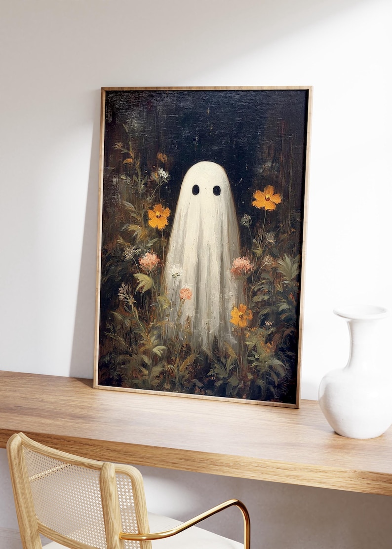 K&ouml;nnte beinhalten: Gerahmter Kunstdruck mit einem wei&szlig;en Geisterwesen mit schwarzen Augen, das inmitten eines Gartens mit orangefarbenen und rosa Blumen steht. Das Kunstwerk hat eine Vintage-&Auml;sthetik, mit dunklem Hintergrund und Holzrahmen. Der Druck wird auf einer Holzoberfl&auml;che pr&auml;sentiert.