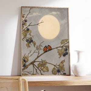 May include: A framed watercolour print depicting a tranquil scene with a large, pale yellow moon in a grey sky. Two ladybirds sit on a branch with leaves and dark berries. The artwork has a vintage aesthetic.