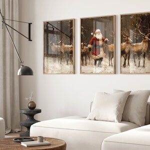 May include: Three framed prints depicting a winter scene with Santa Claus and reindeer. The center print shows Santa Claus in a red suit with a white beard, walking with a group of reindeer. The left and right prints show reindeer walking through a snowy forest.