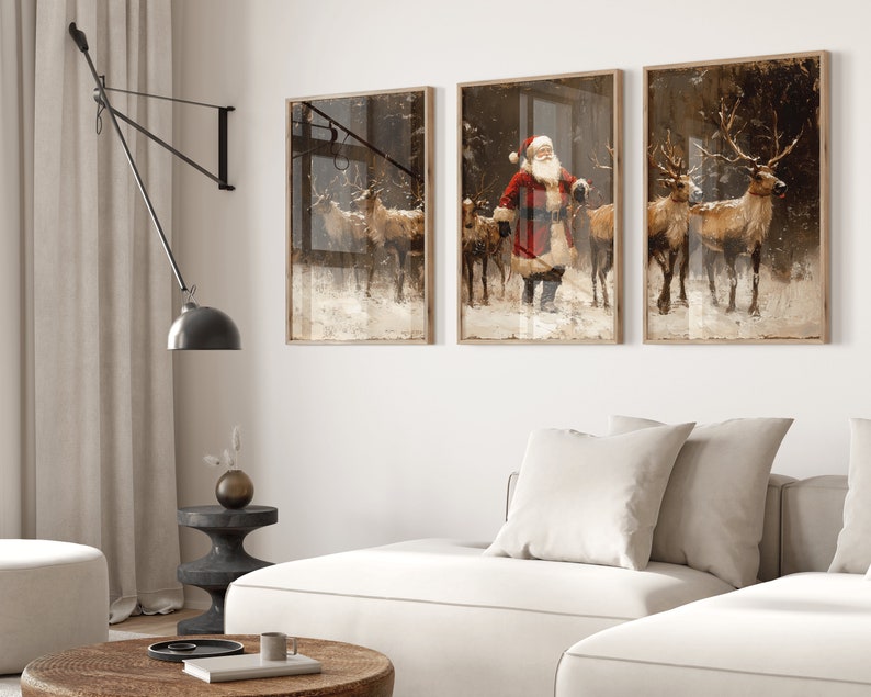 May include: Three framed prints depicting a winter scene with Santa Claus and reindeer. The center print shows Santa Claus in a red suit with a white beard, walking with a group of reindeer. The left and right prints show reindeer walking through a snowy forest.