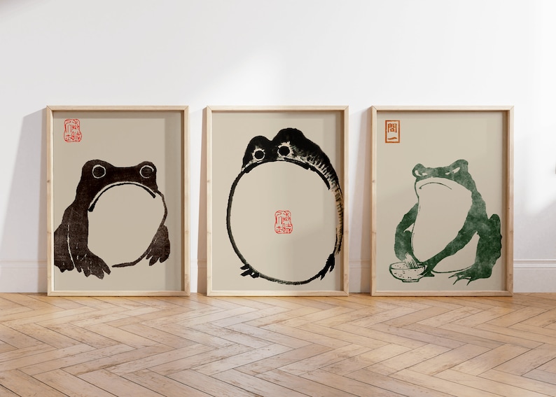 May include: Three framed prints of black and green frogs on a beige background. The frogs are in different poses, one is sitting, one is standing, and one is in a circle shape. Each print has a red or green stamp in the top corner.